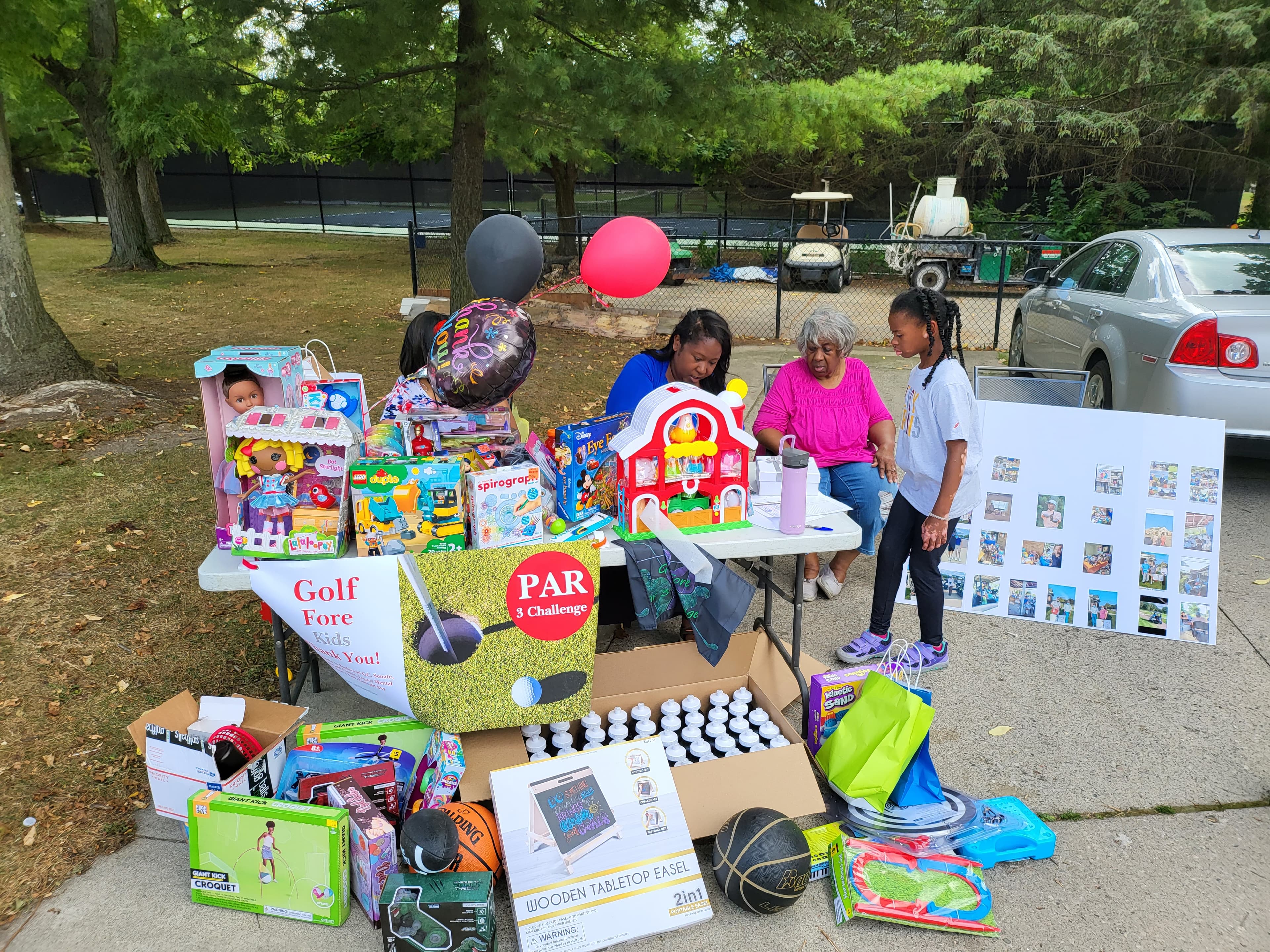 A table overflowing with toys and games for a Golf Fore Kids charity event.