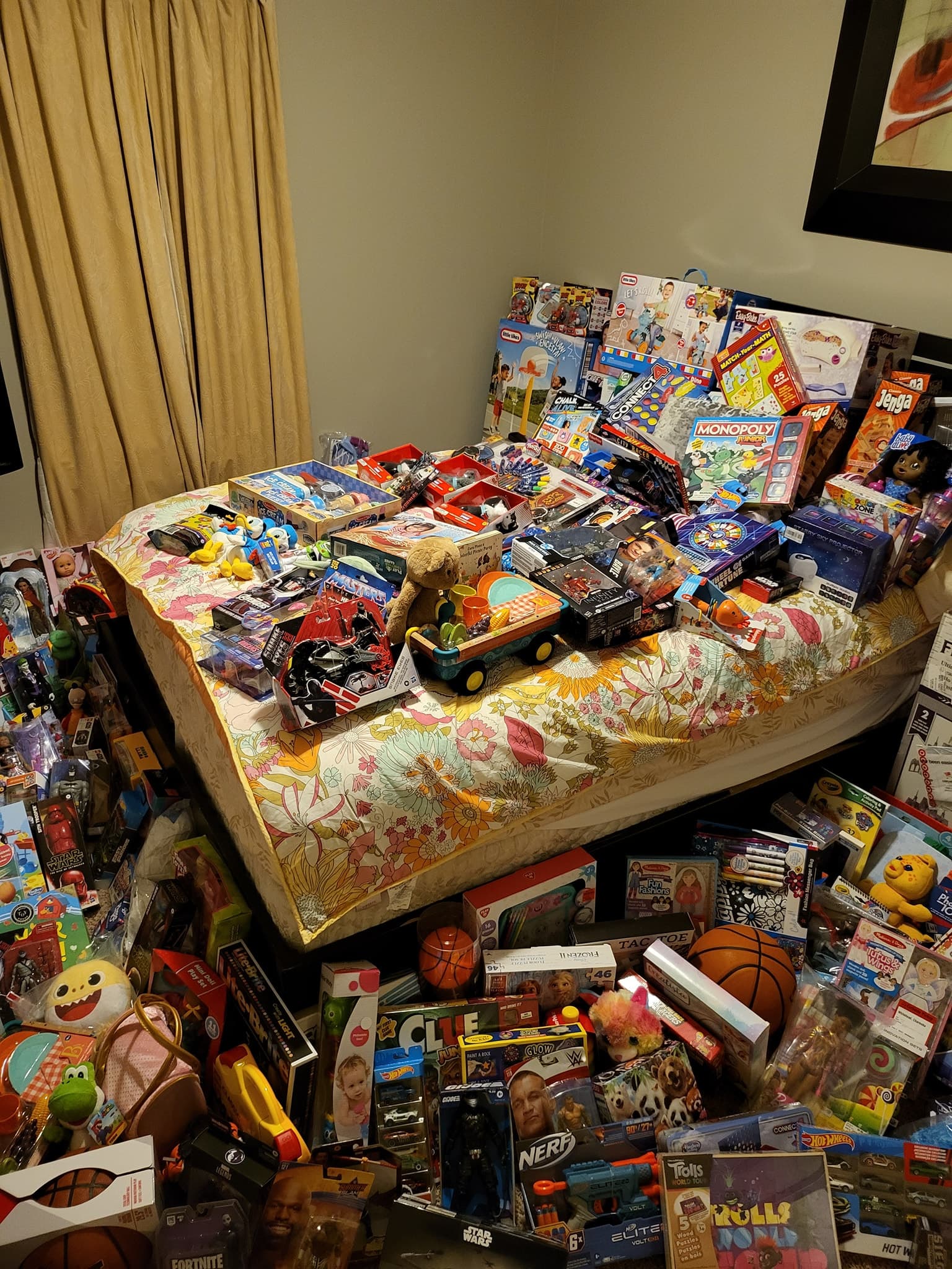 A bed and floor are completely covered in a vast collection of toys and games.
